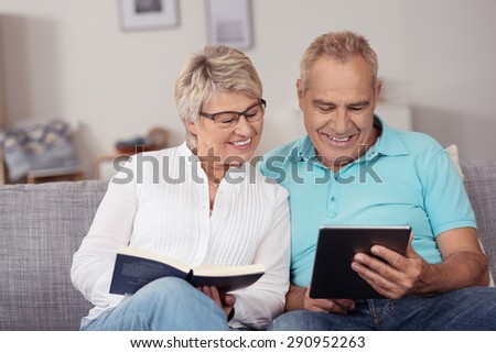 Close up Matured Couple Sitting at the Couch, Watching Something on Tablet Computer with Happy Facial Expression.
