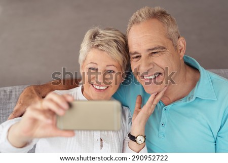 Close up Sweet Happy Middle Aged Couple Sitting at the Couch, Taking Selfie Photo Using Mobile Phone.
