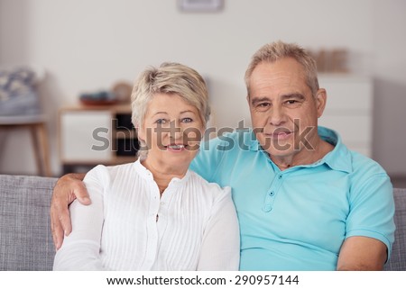 Close up Attractive Middle Aged Couple Sitting on the Couch Inside the House, Looking at the Camera