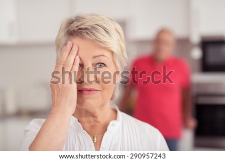 Close up Blond Middle Aged Woman Covering her Face with One Hand While Looking at the Camera.