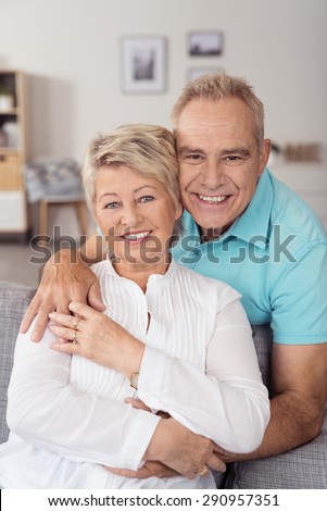 Portrait of a Lovely Middle Aged Husband and Wife at the Living Area, Looking at the Camera with a Toothy Smile.