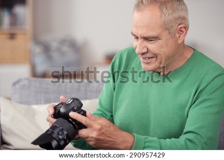 Close up Happy Blond Middle Aged Man Viewing his Captured Pictures on DSLR Camera While Sitting on the Couch.