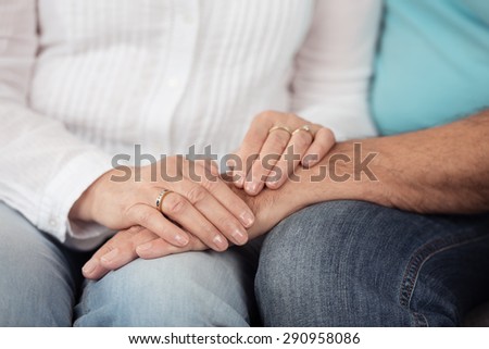 Close up Hands of Romantic Married Couple on Top of their Laps, Emphasizing Love Concept.