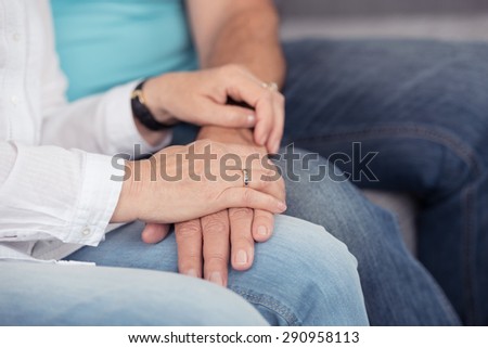 Close up Hands on Top of Laps of Sweet Married Couple in Casual Clothing, Sitting at the Couch.