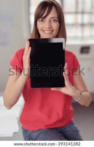 Smiling Woman Holding her Portable Tablet Computer and Showing the Black Empty Screen at the Camera, Emphasizing Copy Space.