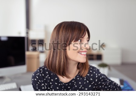 Close up Happy Young Office Woman with Brown Hair, Sitting at her Table While Looking to the Right of the Frame.