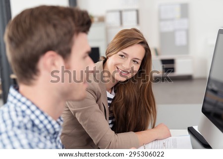 Happy Pretty Young Woman Admiring a Handsome Guy Busy Working with Computer on his Desk Inside the Office.