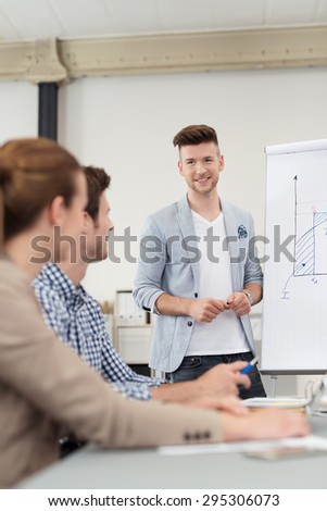 Handsome Young Team Leader Discussing to Members Using a Presentation on a Poster While Having a Meeting Inside the Boardroom.