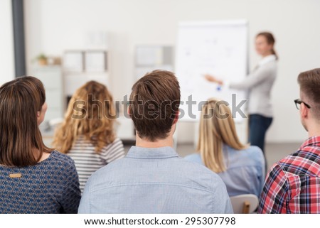 Rear View of Young Office Workers in Casual Outfits Listening to a Top Manager Explaining Something Using Illustrations.