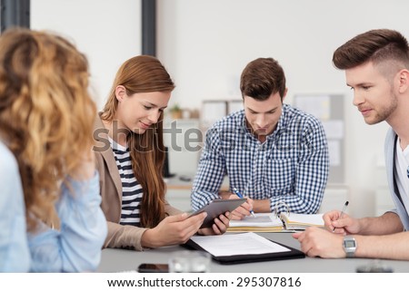 Four Young Professional People In Casual Clothing Having a Business Meeting at the Table Inside the Office