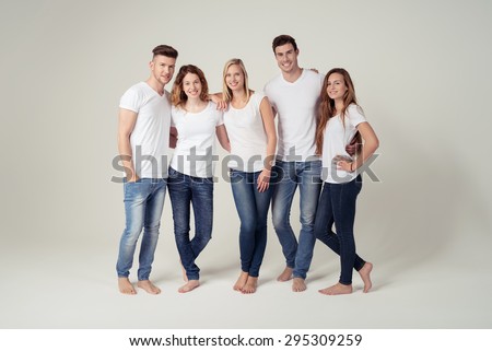 Full Length Shot of Closed Young Friends Smiling at the Camera in Plain White Shirts with Copy Space and Blue Jeans, Captured in Studio on White Background.
