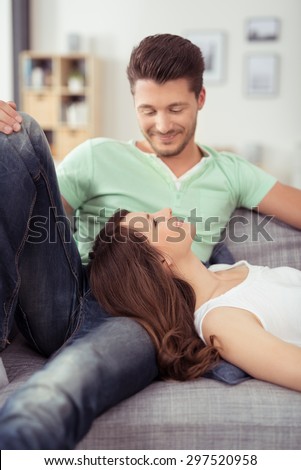 Pretty Young Woman Lying on the Lap of her Handsome Boyfriend at the Couch and Smiling Each Other.