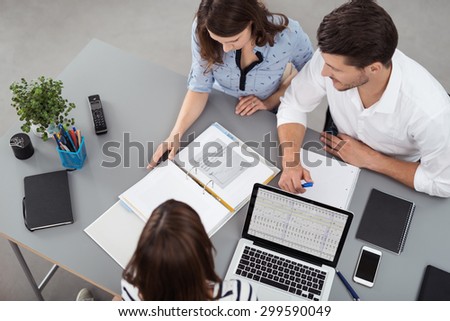 High Angle View of Young Business People Having a Meeting at the Table with Documents and Laptop Inside the Boardroom.