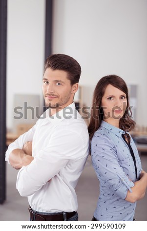 Half Body Shot of Confident Young Business Couple in Back to Back with Arms Crossed Over their Stomach, Looking Straight at the Camera.
