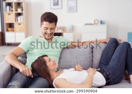 Pretty Woman Lying on Lap of her Handsome Man While Relaxing on Couch In the Living Room and Smiling Each Other