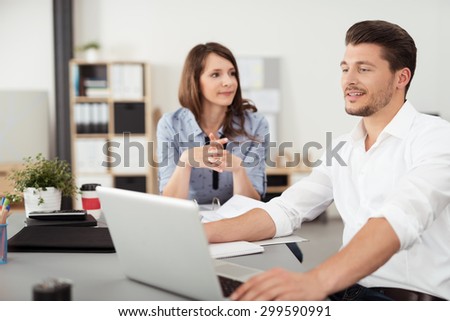 Professional Young Couple Talking About Business While Seated at the Table Inside the Office.