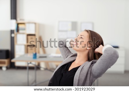 Smiling Pretty Woman Leaning her Back on a Chair with Hands her Head While Relaxing in the Office During her Break Time.
