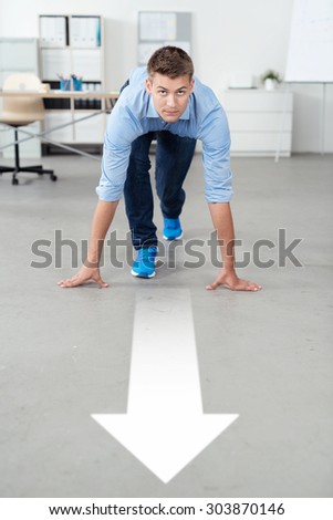 Handsome Young Office Guy in Running Start Position on the Floor with White Arrow, Looking at the Camera.