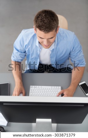 High Angle View of a Young Office Man Sitting at his Table and Working on his Desktop Computer.