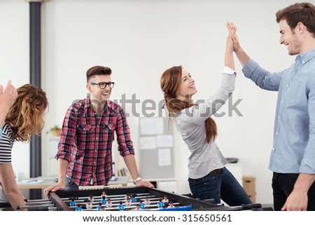 Two Happy Young Workmates Showing High Five After Winning a Table Soccer Game Inside the Office.