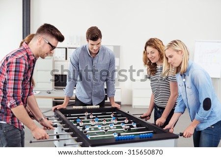 Five Young Office People Enjoying Table Soccer Game During their Free Time at the Workplace.