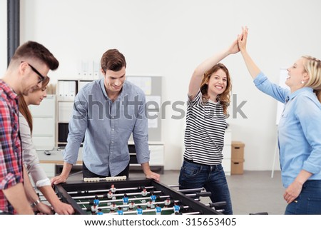 All Girls Office Workers Showing High Five After Winning in Table Soccer Game Against Colleagues During their Break Time.