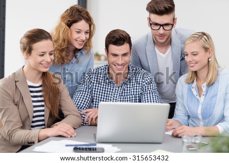 Young Office Workers Watching a Video on Laptop Computer Together with Happy Facial Expressions.