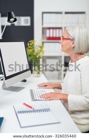 Gray-Haired Middle Aged Businesswoman Working on her Computer at her Desk Inside the Office.