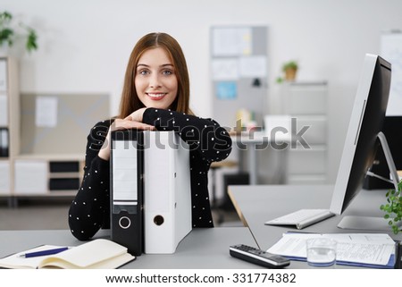 relaxed businesswoman leaning on black and white folders