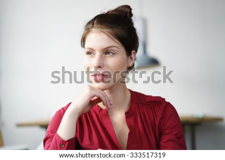Portrait of a Pensive Young Woman with Hand on her Chin, Looking Into the Distance with Half Smile Face.