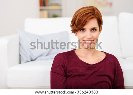 Portrait of a Pretty Young Woman Smiling at the Camera Against White Couch in the Living Area.