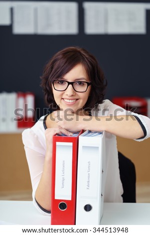 Portrait of a Charming Office Woman Leaning on File Binders on Top of the Table and Looking at the Camera with Happy Facial Expression.