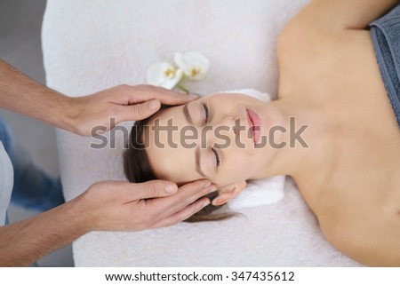 High Angle View of a Young Woman Lying on Bed and Enjoying a Head Massage in the beauty center