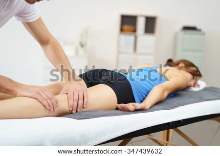Massage Therapist Massaging the Legs of a Woman Lying Prone on the Bed.