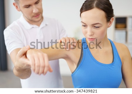 Professional Male Physical Therapist Helping his Female Patient in Exercising the Injured Shoulder.