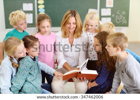 Female Teacher Reading a Story From the Book to her Little Young Students Inside the Classroom