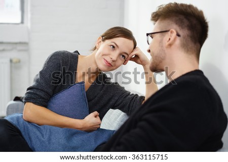 Affectionate young couple relaxing at home sitting on the sofa smiling into each others eyes