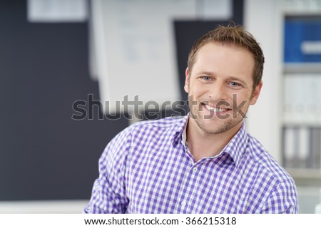 Smiling happy confident businessman looking at the camera with a warm beaming smile, close up head and shoulders with copy space