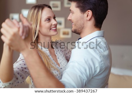 Loving young couple dancing together at home to celebrate a special occasion smiling into each others eyes