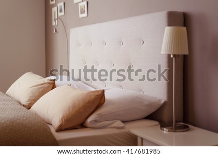 Close up side view of the pillows and headboard of an empty double bed with brown and beige linen