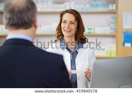 Woman pharmacist helping a male customer dispensing his prescription medicine with a friendly smile