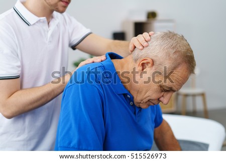 Physiotherapist examining an elderly male patient stretching and re-aligning his neck and vertebrae, close up upper body