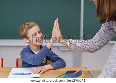 Teacher and happy grinning young student doing a high fives as the schoolboy finally succeeds in understanding something