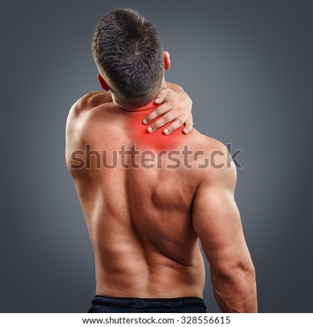 Back view portrait of a man with neck pain over gray background. Concept with highlighted glowing red spot.