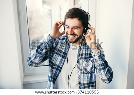 Portrait of a young handsome man with headphones smiling and listening to music