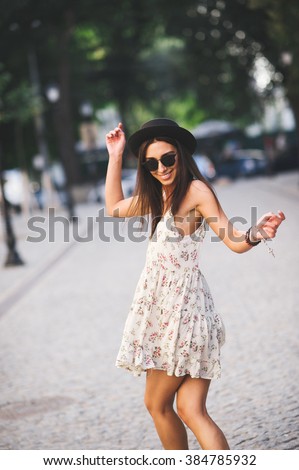 Young pretty woman outdoor fashion portrait. Beautiful girl in summer dress and sunglasses dancing on the street