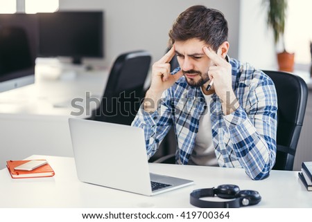 Tired man working on the laptop in the office. Business man wearing casual clothes thinking about a problem at his computer