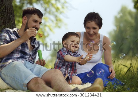Happy family. Mother, father and son blowing bubbles in the park