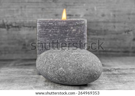 zen composition, a grey stone and a grey candle on wooden background