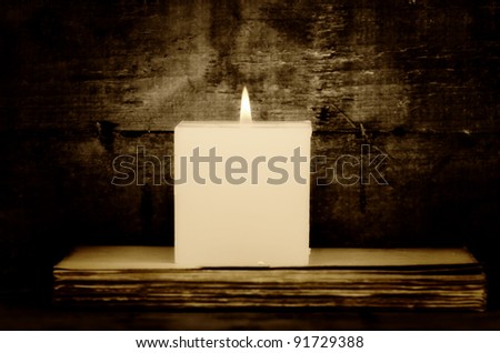 an old book with a candle  on wooden background